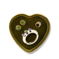 a green heart shaped tray with rings and earrings in it, on a white background