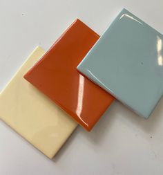 three different colored ceramic tiles on a white surface