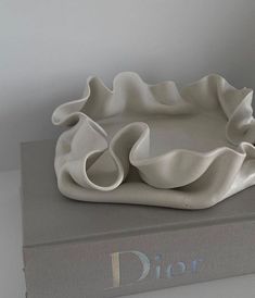 a white ceramic dish sitting on top of a book with the word dior written below it