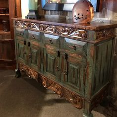 an old wooden cabinet with carvings on the top and bottom, sitting in a room