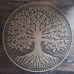 a white doily with a tree on it sitting on top of a wooden table