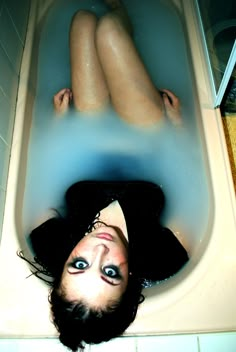 a woman laying on the floor in a bathtub