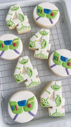 decorated cookies in the shape of numbers and characters are arranged on a cooling rack for display