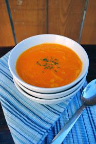 two bowls of soup are sitting on a blue and white tablecloth with spoons