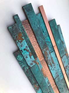 three pieces of art made out of copper and green pattered metal on a white wall