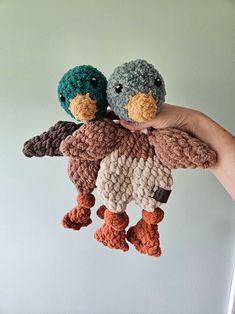 two crocheted stuffed birds are held in the air