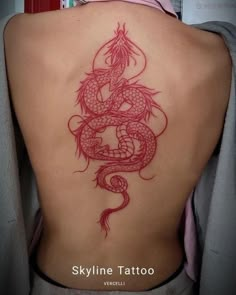 a woman's back with a red dragon tattoo on it