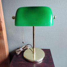 a green lamp sitting on top of a wooden table next to a phone charger