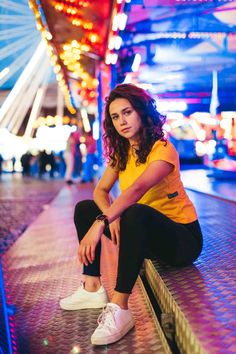 a woman sitting on the ground in front of a ferris wheel