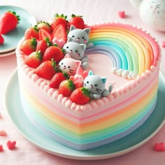 there is a heart shaped cake decorated with cats and rainbows on it, along with strawberries