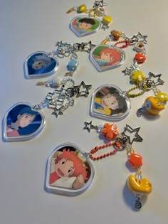 many different necklaces with cartoon characters and charms attached to them on a white surface