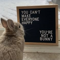 a rabbit sitting next to a sign that says you can't make everyone happy