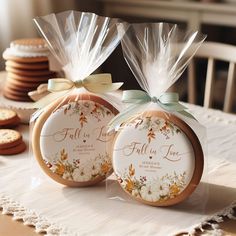 two cookies wrapped in clear cellophane and tied with bows on a table next to each other