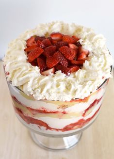 a cake with strawberries on top is in a glass dish, ready to be eaten