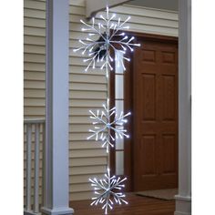 a lighted snowflake hanging from the side of a house in front of a door