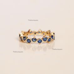 a gold ring with blue sapphire stones on it's sides, sitting on a white surface