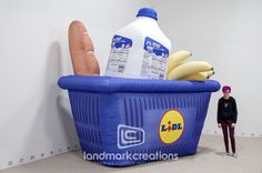 a giant hot dog in a basket next to a large bottle of milk and some bananas