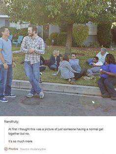 two men standing in front of a group of people sitting on the ground next to each other