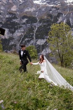 a bride and groom holding hands in the mountains