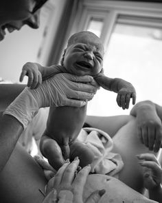 a baby being held up in the air by its mother's hands and dad holding him