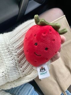 a person holding a red stuffed strawberry in their hand with a smile on it's face