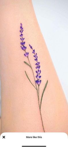 a small purple flower on the side of a woman's arm, with words above it