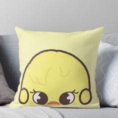 a yellow bird with big eyes on it's head sitting on a couch throw pillow