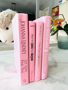 three pink bookends sitting on top of a counter next to a stuffed animal