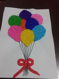 a bunch of balloons on top of a piece of paper with a red ribbon around it