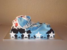 a shoe cake with blue and white icing on top, sitting on a table