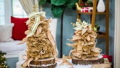 two decorated christmas trees sitting on top of snow covered logs