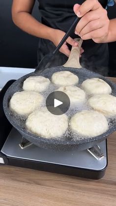 a person cooking food in a pan on top of a stove