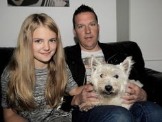 a man and woman sitting on a couch with a dog