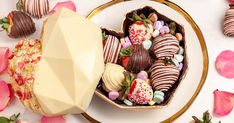 chocolate covered strawberries in a heart shaped box on a plate with pink flowers around it