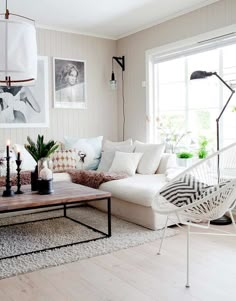 a living room with white furniture and pictures on the wall above it's coffee table