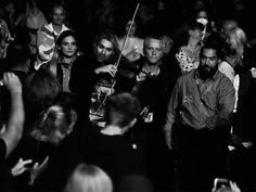 a group of people standing around each other in front of a crowd with one person holding a violin