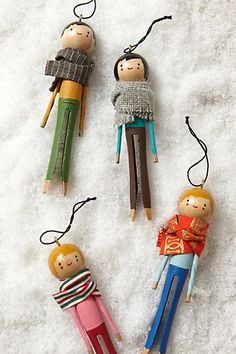 three wooden dolls hanging from strings in the snow