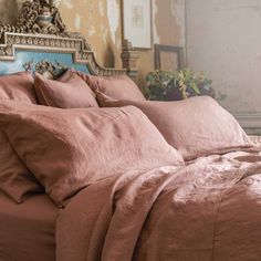 a bed with pink sheets and pillows in a room that has peeling paint on the walls