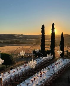 a long table is set up with white linens and place settings for an outdoor dinner