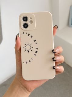 a woman holding up her phone case with the words live by the sun on it