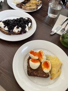 two white plates topped with food on top of a wooden table