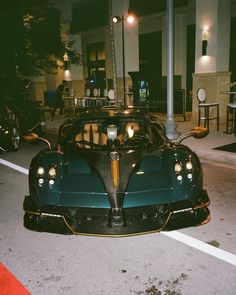 a blue and black sports car parked in front of a building on the street at night