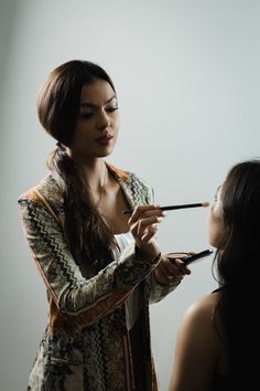 a woman is doing makeup on another woman