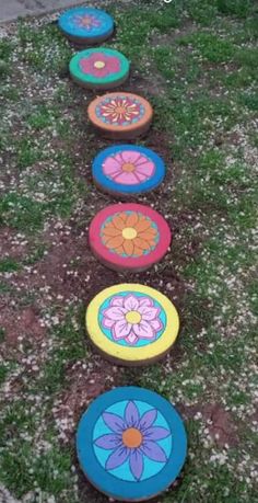 painted stepping stones in the grass with flowers on them