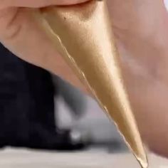 a close up of a person writing on paper with a gold colored object in the background