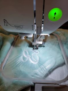 the sewing machine is on and has green light coming from it's blades