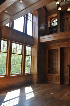 an empty room with wood paneling and windows