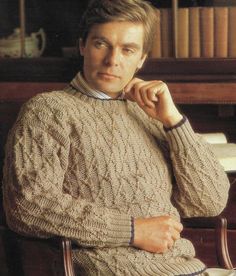 a man sitting in a chair wearing a sweater