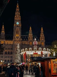 people are walking around in front of an ornate building with christmas lights and decorations on it