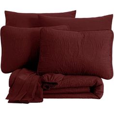 the bedding is made up with red sheets and pillows on top of each other